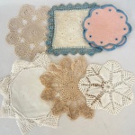 Lote com 11 (onze) porta copos em linho e bordados, Diversos formatos e cores, med. maior 17cm de diâmetro. Apresenta manchas