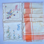Lote com 7 peças, sendo: 5 guardanapos em linho com xadrez na cor laranja e creme, med. 38X38cm, e 2 porta grardanapos em linho com flores e monograma bordados, med. 20X20cm