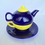 Bule de chá com xícara acoplada e pires para servir em porcelana nas cores amarelo e azul. Med.: 12cm de altura e 18cm de largura. Pires com 18cm de diâmetro.