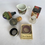 Lote com 6 (seis) peças sendo 2 salvagocce para vinho (para não escorrer vinho) em metal; 1 dosador para vinho em resina com decoração de cacho de uva; 1 rolha  com metal; 1 mini leiteira em porcelana com paisagem de Estônia com 5cm de altura; e 1 pequeno saleiro de vidro com tampa em inox da marca Meridional com 4cm de altura.