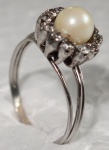 Um anel em ouro 18K , com 13 diamantes e uma pérola no cento - Aro: 24 - Peso: 4.7 Gramas.