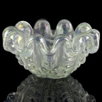 BAROVIER, ERCOLE -  BAROVIER & TOSO  GRANDE BOWL EM FORMATO DE GRANDE CONCHA, OBRA ENTITULADA 'A GROSSE COSTOLATURE'. ROBUSTO BLOCO DE VIDRO ARTÍSTICO DE MURANO IRIDESCENTE. ESTILO E ÉPOCA ART DECO. A INCIDÊNCIA DA LUZ PRODUZ FAISCANTES HALOS NA COR DO ARCO IRIS. PRODUZIDO  NA OFICINA DE BAROVIER & TOSO NA DÉCADA DE 1940. BELISSIMA PRODUÇÃO DO PRINCIPAL E MAIS ANTIGO MESTRE VIDREIRO DE MURANO, TRADIÇÃO FAMILIAR INICIADA COM A PRIMEIRA FÁBRICA NO ANO DE 1295. REPRODUZIDO NO CATÁLOGO RAIZONNE DO ARTISTA PAG 148 MARINA BAROVIER L'ARTE DEI BAROVIER VETRAI DI MURANO 1866-1972 ARSENALE VENEZIA 1993 P. 148.. PARA SUA COMPARAÇÃO VEJA UMA PEÇA DESSA SÉRIE ANUNCIADA PARA VENDA POR  6000 EUROS: https://www.pamono.de/seashell-schale-von-ercole-barovier-fuer-barovier-and-toso.   ITÁLIA, DEC. DE 1940.19 X 11 CMNOTA: Barovier & Toso é a mais antiga fábrica de vidro Muranês fundada em 1295. No início de 1900, Benvenuto Barovier, Vittorio Zecchin e Umberto Belotto projetaram uma série de vidros de mosaico em estilo liberty. Em 1920 Ercole Barovier tornou-se diretor artístico. Sob sua direção, Barovier, Barovier & Toso ganharam inúmeros prêmios por suas inovações. Em 1930, a premiada série "Primavera" foi apresentada na Bienal de Veneza. Barovier continuou a produzir designs inovadores. Vários deles tornaram-se icónicos, como o 'Lenti', o 'Crepuscolo', o 'Autunno Gemmato', o 'Oriente', o 'Rostrato', o 'Tessere' e o 'Barbarico' - só para citar alguns. A empresa tornou-se Ferro Toso Vetrerie Artistiche Riunite S.A em 1936, quando a Vetreria Artistica Barovier se fundiu com a Ferro Toso. Em 1942, a empresa foi renomeada para Barovier & Toso. A empresa também executou projetos de e. g. Matteo Thun, Giusto e Renato Toso, Toni Zuccheri e Sergio Asti.