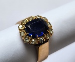 Belíssimo anel em ouro 18k com 12 brilhantes e pedra azul na parte central. Peso; 6.3g. Aro; 20.