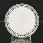Delicada <B>salva</b> circular em prata inglesa, apresentando fundo liso e aba fenestrada intercalada por pequenas urnas com borda perolada. Triplos pés frisados. Contraste da cidade de Birmingham de 1931 e marca da casa MAPPIN & WEBB. Peso 210 gramas. Diâm. 17,5 cm