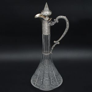 <b>Garrafa</b> "claret jug" em cristal da Bohemia. Apresenta lapidação em flores geometrizadas com gargalo e tampa em prata 850 ml. Provavelmente de São Paulo. Alt. 44 cm