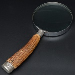 <b>Lupa </b>inglesa com cabo em osso arrematado em Old Sheffield lavrado com cachos de uvas e folhas de parreira. Compr. 26,5 cm