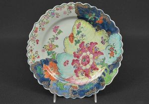 <b>Prato raso</b> de borda ondulada em porcelana Companhia das Índias decorada em rica policromia Família Rosa no padrão dito "Folha de Tabaco". Inspirava-se não exatamente nas folhas de tabaco e sim na luxuriante vegetação do sudeste asiático e das ilhas do oceano pacífico. Séc. XVIII. Diâm. 22,5 cm