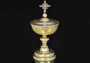 <b>Âmbula</b> em prata com resquícios de "vermeil" em prata brasileira. Haste em segmentos de balaústre sobre base circular abobadada. Tampa sobreposta por cruz sem marcas. Séc. XVIII. Peso 255 gramas. Alt. 17 cm