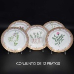 <b>Conjunto de 12 pratos para sobremesas </b>em porcelana dinamarquesa da importante manufatura Royal Copenhagen, modelo <b>"Flora Danica"</b>. Cada peça, inteiramente pintada à mão em belíssima policromia com suas designações botânicas e numeração no verso. Apresentam bordas em mínimos picotados cobertos a folha de ouro. Diâm. 19,5 cm