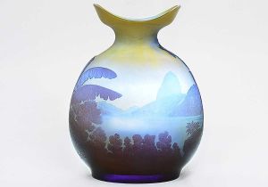 <b>EMILE GALLÉ - Rio de Janeiro - Vaso </b>globular com bocal de forma navicular em "cameo glass" de tonalidade levemente amarelada e diversas nuances de azul. Em uma das faces o Morro do Corcovado tomado da enseada de Botafogo com seu casario e do outro, o Morro da Urca e o Pão de Açúcar. Exuberantes palmeiras e bananeiras nas laterais e outros vegetais completam o conjunto. Assinado. Alt. 22,5 cm