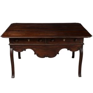 Belíssima <b>mesa colonial </b>brasileira construída em jacarandá. Tampo retangular de quinas arredondadas sobre duas gavetas dispostas lado a lado com espelho das fechaduras em osso e puxadores modelados em pião. Saia em recortes e pernas recurvadas. Minas Gerias. Séc. XVIII.  Med. 80 x 153 x 121 cm