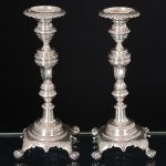 <b>Par de castiçais</b> em prata brasileira Império, decorados com guilhochados e lavrados com folhagens. Receptáculos com bordas em ondulações e pés em garras sobre bolas. Marcas de prateiro e "10 Dinheiros". Séc. XIX. Alt. 23 cm. Peso 735 gramas.