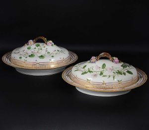 Excepcional <B>par de legumeiras ovais com tampa</b> em porcelana dinamarquesa da importante manufatura Royal Copenhagen, modelo <B>"Flora Danica"</b>. Cada peça, inteiramente pintada à mão em belíssima policromia com suas designações botânicas e numeração no verso. Apresentam bordas em mínimos picotados cobertos a folha de ouro. Med. 40 x 32 cm