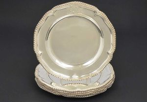 <b>ROBERT GARRARD - Conjunto de 6 "sousplats" </b>em prata inglesa George IV. Apresentam brasão armorial lavrado e borda movimentada em godrões. Contraste da cidade de Londres de 1827 e marca do prateiro real britânico ROBERT GARRARD. Diâm. 25,5 cm. Peso 3915 gramas.