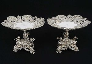<b>Par de belíssimas fruteiras "dessert stands" </b>em prata inglesa do período vitoriano. Apresenta pratos com rendados no estilo renascentista centralizando monograma da rainha Victoria, Victoria Regina, sob coroa e haste em segmento de balaústre perolado com base apresentando figuras infantis. Contraste da cidade de Londres de 1868 e marca do prateiro ROBERT GARRARD II. Peso 2780 gramas. Alt. 20 cm; Diâm. 25 cm