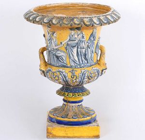 Rara <b>ânfora </b>portuguesa em cerâmica Santo Antônio do Porto decorada com diversas figuras em relevo em tonalidades de azul sobre fundo amarelo. Acompanha base em madeira. Séc. XVIII. Imperfeições do tempo. Alt. da ânfora 55 cm; Alt. total 70 cm