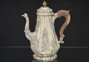 Robusta <B>cafeteira </b>piriforme em prata portuguesa decorada em seções decoradas com flores, "coquilles", angras e volutas. Alça e pega da tampa em madeira. Prováveis contrastes de Lisboa do início do séc. XVIII e vestígios de marca de prateiro.  Alt. 29 cm. Peso 1470 gramas.