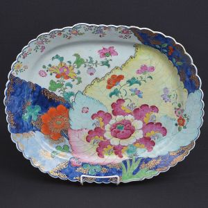 Grande <b>travessa</b> de borda recortada em porcelana Companhia das Índias. Decoração com esmaltes da Família Rosa no padrão Folha de Tabaco, conhecido por representar toda a riqueza e pujança da flora das ilhas do oceano pacífico, tendo em primeiro plano grande flor de hibisco. Reinado Qianlong. Séc. XVIII. Compr. 46 cm