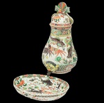 Raro<b> filtro e sua bacia </b>em porcelana Companhia das Índias decorada em policromia nos esmaltes da Família Verde com inúmeros elementos do mar. O filtro piriforme com torneira metálica modelada em cabeça de delfim possui tampa semi abobadada. A bacia de forma oblonga é modelada em gomos. Predominância das tonalidades de verde, "rouge de fer" e castanho sobre fundo branco. Circa 1700. Reinado Kangxi. Alt. do filtro 47 cm; Med. da bacia 35 x 27,5 cm