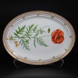 <b>Grande travessa oval </b>em porcelana dinamarquesa da importante manufatura Royal Copenhagen, modelo <b>"Flora Danica"</b>. Inteiramente pintada à mão em belíssima policromia com suas designações botânicas e numeração no verso. Apresenta borda em mínimos picotados cobertos a folha de ouro. Med. 44 x 33,5 cm