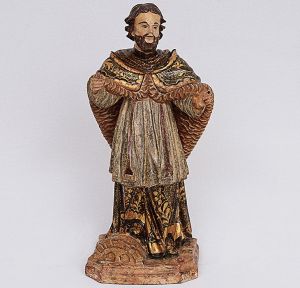 <b>MESTRE PIRANGA</b> - Belíssima imagem de <b>São Gonçalo</b>, mineira, em madeira entalhada. O santo, de finas feições, apresenta-se de pé, com os braços parcialmente abertos. Vestes plissadas e longo manto, caído em ponta, na parte posterior, ambos em policromia, com ricos realces floridos e perolados a ouro sobre fundo negro. Base chanfrada. Minas Gerais. Séc. XVIII. Alt. 43 cm