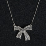 <b>Colar</b> em ouro branco 18k, "laço", com centro cravejado com "baguettes" e brilhantes. Peso 8,2 gramas.