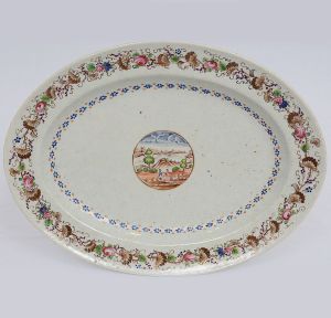 <b>José Pinheiro Freire. Travessa</b> oval em porcelana Companhia das Índias do serviço conhecido como "Paquetá". José Pinheiro Freire foi médico na Bahia e posteriormente no Rio de Janeiro e residia na Ilha de Paquetá, na Baia de Guanabara. Reserva ao centro onde acredita-se que a paisagem seja da Ilha de Paquetá. Borda tipicamente portuguesa com flores, folhas de parreira e cachos de uvas. Circa 1825. Referências bibliográficas à pág. 308 do livro "A Porcelana Chinesa ao Tempo do Império", por Nuno de Castro. Med. 30,5 x 23 cm