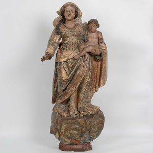 Grande e belíssima imagem de <b>Nossa Senhora com o Menino Jesus</b>, brasileira, em madeira. A santa encontra-se de pé com elaboradas vestes, de corpete acinturado, e caídas em plissados espraiados sobre a base. Magnífica policromia com flores de tonalidade rosada sobre fundo verde azulado. Realces a ouro. Pano da cabeça movimentado entrevendo-se parcialmente o cabelo em ondulações. Minas Gerais. Primeira metade do séc. XVIII. Faltam os braços do menino. Alt. 102 cm