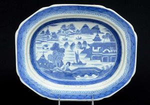 <b>Travessa funda</b> de forma retangular com cantos levemente chanfrados, em porcelana chinesa de Macau decorada em azul índigo com cena lacustre, pagodes e borda em arabescos. Séc. XVIII. Med. 38 x 27 cm