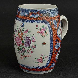 <B>Caneca "mug" </B>em forma de barril, em porcelana Companhia das Índias profusamente decorada em policromia florida com insetos e arabescos. Alça recurvada. Séc. XVIII. Alt. 13 cm
