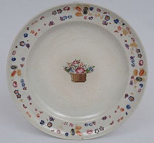 <b>Manoel Machado Coelho de Castro - Prato</b> circular em porcelana Companhia das Índias, decorado em policromia Família Rosa, apresentando cesto de flores ao centro e borda com frutos e flores com vestígios de ouro. Séc. XIX. Referências bibliográficas à pág. 116 do livro "Louça da Aristocracia no Brasil", por Jenny Dreyfus. Diâm. 20 cm