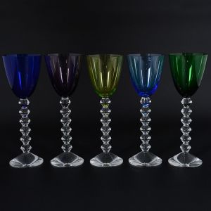 Lote constando de: a) <b>5 taças de pé alto</b> em cristal BACCARAT apresentando bojo de diversas cores e hastes em elementos balonados superpostos. Marca da "cristallerie" no verso. Alt. 23,5 cm; b) <b>4 taças de pé alto</b> cristal com bojo na cor verde esmeralda, hastes facetadas e bases estreladas. Marca da "cristallerie" no verso. Alt. 20,5 cm