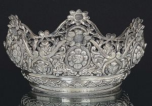 Grande e rara <b>coroa de santa Mártir </b>em prata brasileira profusamente decorada em vazados com botões de flores e cercadura de goivos na base. Séc. XVII / XIX. Peso 525 gramas. Alt. 12,5 cm; Diâm. 29,5 cm