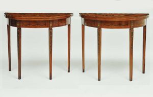 <b>Par de consoles </b>ingleses em forma de meia lua, reversíveis para mesas circulares, construídos em madeira nobre no estilo Adam. Pernas retas facetadas, sendo uma pivotante e bela pintura policromada com flores e perolados. Séc. XIX. Med. 77 x 85 x 43 cm