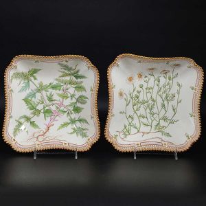 <b>Par de "bowls" </b>quadrados em porcelana dinamarquesa da importante manufatura Royal Copenhagen, modelo <b>"Flora Danica"</b>. Cada peça, inteiramente pintada à mão em belíssima policromia com suas designações botânicas e numeração no verso. Apresenta borda em mínimos picotados cobertos a folha de ouro. Med. 23 x 23 cm