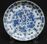 <b>Covilhete</b> circular com borda levemente movimentada em porcelana Companhia das Índias, decorado com composições floridas em azul índigo "underglaze" sobre fundo branco. Período Kangxi. Parte da borda com restauro. Diâm. 25,5 cm