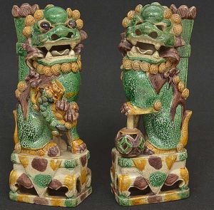 <b>Casal de cães de fó </b>em cerâmica chinesa, decorados em policromia verde e amarelo. Séc. XVIII. No verso selo da Packing Shop - London. Um deles sem os olhos. Alt. 20,5 cm