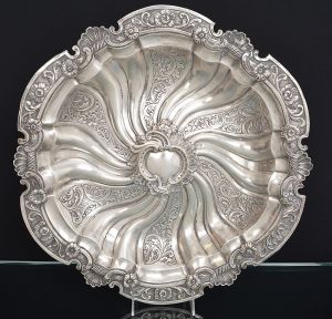 <b>Medalhão </b>circular em prata portuguesa decorada com belas composições barrocas em gomos e volutas levemente torcidos. Borda recortada com flores e elementos concheados. Contraste da cidade do Porto usado de 1886 a 1938. Peso 880 gramas. Diâm. 46,5 cm