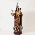 Grande imagem de <b>Nossa Senhora com o Menino Jesus</b>, em madeira, com vestes policromadas e entalhadas em diversas direções. Manto arrebanhado ao braço esquerdo onde pousa o Menino. Pano de cabeça com estrelinhas. A imagem está descalça sobre enrolado de nuvens com três querubins à frente. À mão esquerda um ramo de flores. Séc. XIX. Alt. 97 cm