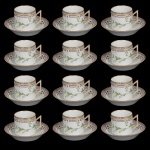 <b>Conjunto de 12 xícaras de café com pires</b> em porcelana dinamarquesa da importante manufatura Royal Copenhagen, modelo <b>"Flora Danica"</b>. Cada peça inteiramente pintada à mão em belíssima policromia com suas designações botânicas e numeração no verso. Apresenta borda em mínimos picotados cobertos a folha de ouro. Alt. da xícara 6,5 cm; Diâm. do pires 14 cm