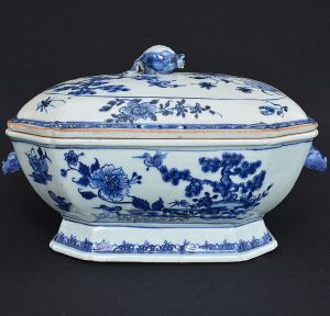 <b>Terrina</b> retangular de cantos chanfrados em porcelana chinesa decorada em azul índigo "underglaze" sobre fundo branco com flores, árvores e figuras de aves em paisagem com terraço. Pegas do bojo modeladas em cabeças de lebres e da tampa em romã. Séc. XIX. Compr. 36 cm; Alt. 22,5 cm