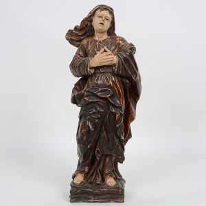 Imagem de <B>Santa Maria Madalena</b>, brasileira, em madeira. A imagem encontra-se de pé com as mãos postadas ao peito e possui vestes e manto patinados em tonalidade escura, deixando entrever seus pés descalços. Olhos em contas. Séc. XVIII. Alt. 39,5 cm