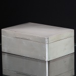 <b>Caixa</b> retangular em prata inglesa. Apresenta bojo liso com tampa guilhochada. Contraste da cidade de Birmingham de 1921 e marca do prateiro W N & S L. Med. 6,5 x 16,5 x 11,5 cm