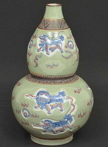 Antigo <b>vaso</b> chinês em porcelana na forma de bulbo, decorado com animais bizarros sobre fundo craquelê verde celadon. Marcas no verso. Alt. 38 cm