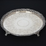 <b>Salva</b> circular em prata brasileira "União", apresenta fundo belamente gravado com composições vegetais e galeria vazada com volutas. Pés em garras. Diâm. 33,5 cm