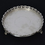 <b>Salva</b> circular em prata, apresentando fundo lavrado, galeria vazada com flores e triplos pés em garras. Contrastes portugueses. Diâm. 15,5 cm