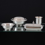 <b>Conjunto de peças em prata </b>portuguesa decoradas em guilhochados sendo duas delas monogramadas. Constando de "bowl" com tampa para flores, caixa ovalada, copo e pequena bacia. Contraste "Javali" da cidade do Porto usado de 1886 a 1938 e marca de prateiro. Alt. do copo 9 cm; Compr. da caixa oval 22 cm. Peso 1300 gramas.