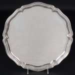 <b>Bandeja</b> circular em prata alemã lisa, 925 ml, apresentando borda ondulada intercalada com folhas de acanto. Diâm. 33 cm. Peso 660 gramas.