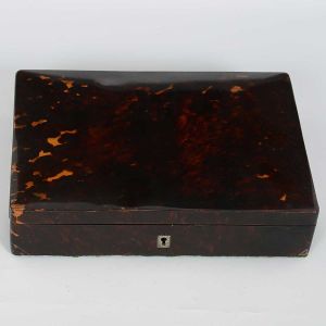 Antiga<b> caixa</b> retangular inglesa revestida em casco de tartaruga loura com interior em seda e veludo verde. Acompanha chave. Med. 6 x 27 x 20 cm