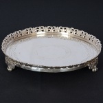 <b>Salva</b> circular em prata, apresentando fundo gravado com folhagens, galeria vazada e três pés em garras. Contrastes portugueses. Diâm. 21 cm. Peso 400 gramas.